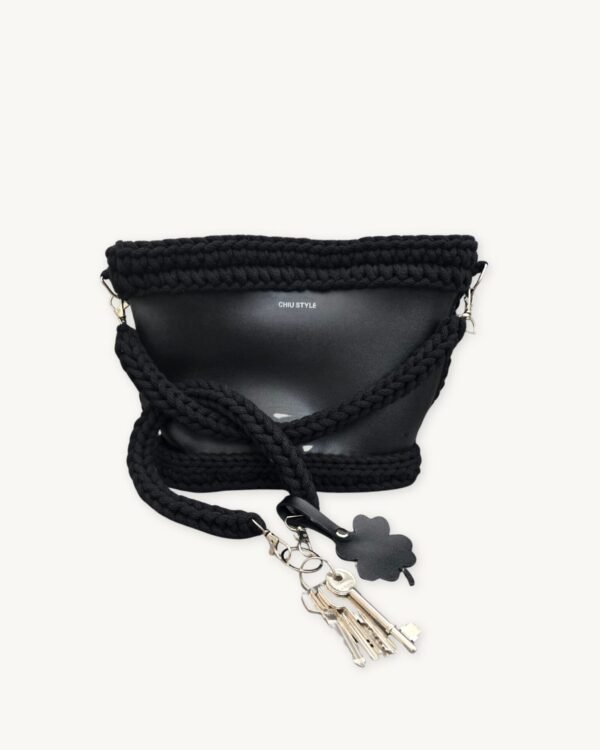 Black clover vegan leather braided keychain looped around a tote bag handle, demonstrating easy key access inside a handbag