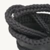 Close-up detailed view of the black clover vegan leather braided keychain looped around a handbag handle inside a tote