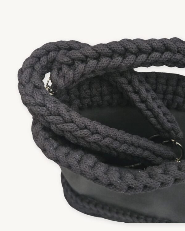 Close-up detailed view of the black clover vegan leather braided keychain looped around a handbag handle inside a tote