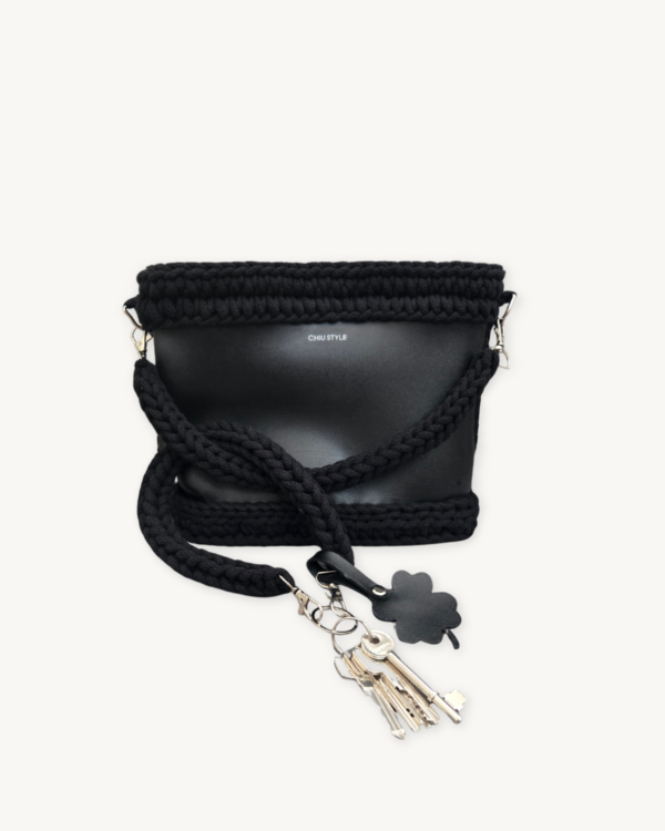 Black clover vegan leather braided keychain looped around a tote bag handle, demonstrating easy key access inside a handbag