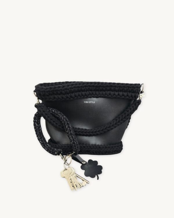 Black with silver thread clover vegan leather braided keychain looped around a tote bag handle, demonstrating easy key access inside a handbag
