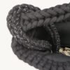 Close-up detailed view of the black with silver thread clover vegan leather braided keychain looped around a handbag handle inside a tote