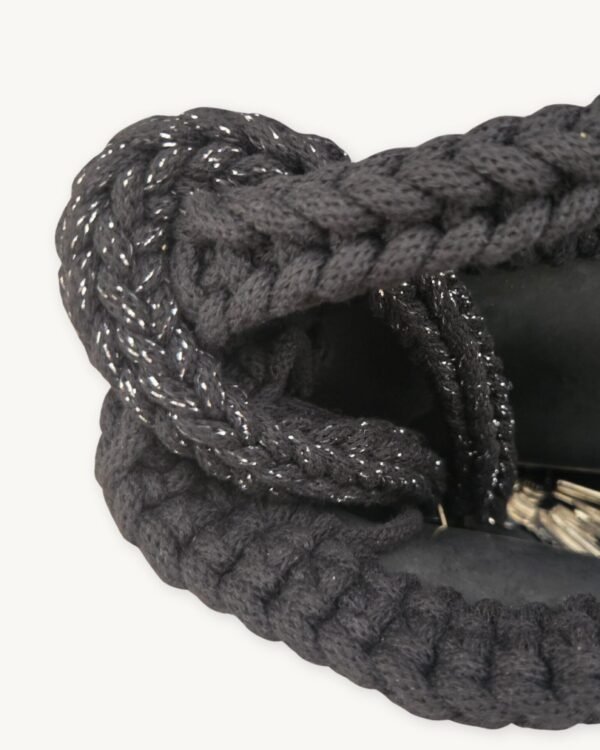 Close-up detailed view of the black with silver thread clover vegan leather braided keychain looped around a handbag handle inside a tote