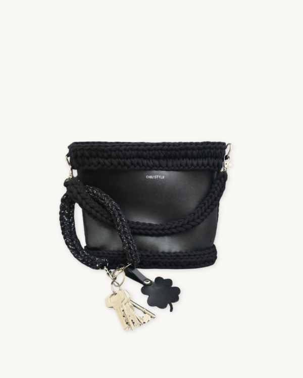 Black with silver thread clover vegan leather braided keychain looped around a tote bag handle, demonstrating easy key access inside a handbag