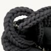 Close-up detailed view of the black vegan leather braided keychain looped around a structured leather handbag handle inside a tote