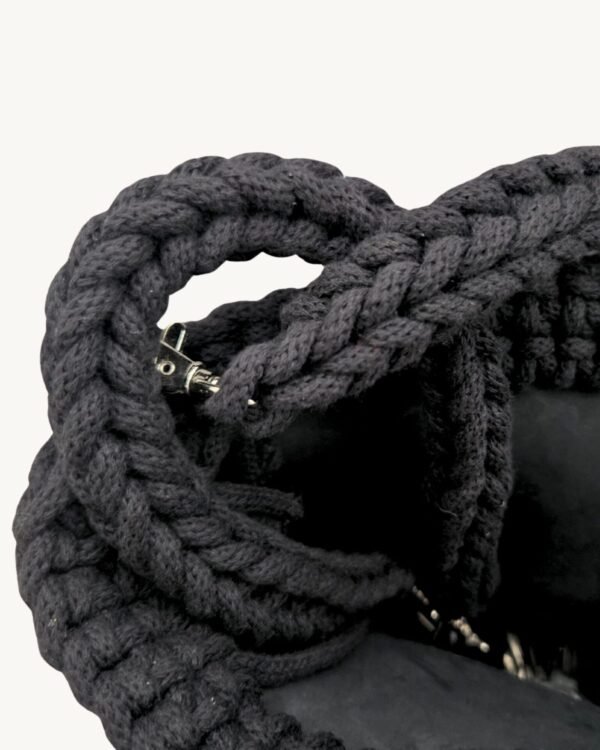 Close-up detailed view of the black vegan leather braided keychain looped around a structured leather handbag handle inside a tote