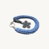 Angled side profile of the CHIU STYLE floral vegan leather braided keychain in Cornflowers Blue resting on a natural wood surface, highlighting texture and floral tag
