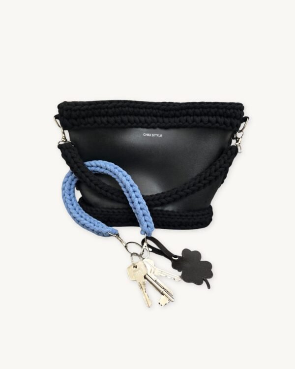 Cornflower blue clover vegan leather braided keychain looped around a tote bag handle, demonstrating easy key access inside a handbag