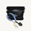 Cornflower blue clover vegan leather braided keychain looped around a tote bag handle, demonstrating easy key access inside a handbag