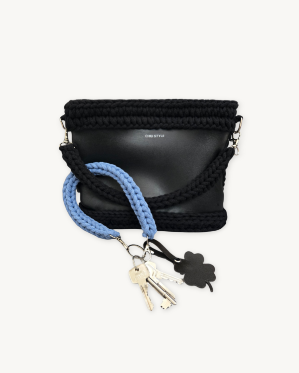 Cornflower blue clover vegan leather braided keychain looped around a tote bag handle, demonstrating easy key access inside a handbag