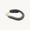 Angled side profile of the CHIU STYLE vegan leather braided keychain in Earth Mocha resting on a natural wooden surface, highlighting the texture and warm brown logo tag