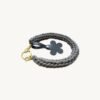 Angled side profile of the CHIU STYLE floral vegan leather braided keychain in mocha brown resting on a natural wood surface, highlighting texture and floral tag