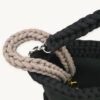 Close-up detailed view of the mocha floral vegan leather braided keychain looped around a handbag handle inside a tote