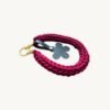 Angled side profile of the CHIU STYLE floral vegan leather braided keychain in Sangria resting on a natural wood surface, showcasing texture and floral tag