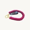 Angled side profile of the CHIU STYLE vegan leather braided keychain in Sangria resting on a natural wood surface, showcasing texture and warm brown tag