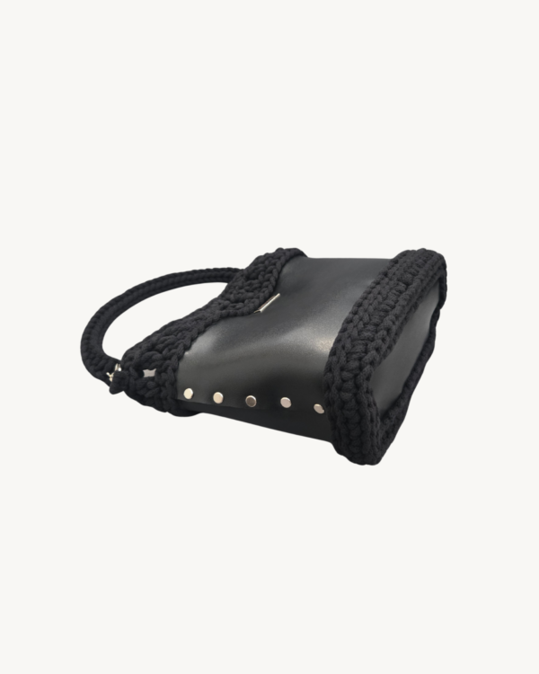 Side-lying view of Vintage Punk Vegan Leather Laced Rhythm Handbag in black showing the structured bottom, Chicago screws, and crochet texture