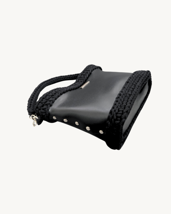Black Vintage Punk Vegan Leather Classic Handbag resting sideways on a table showing the structured bottom view