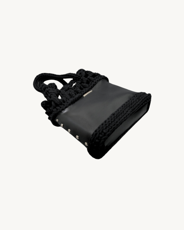 Side-lying view of the Vintage Punk vegan leather black drawstring bag, showcasing the structured bottom and reinforced side construction.