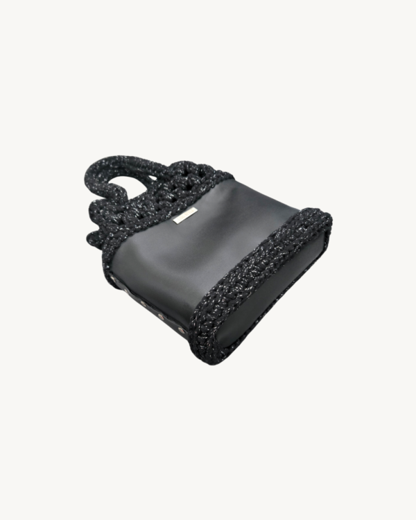 Side-lying view of the Vintage Punk vegan leather drawstring bag in black with silver thread, showcasing the structured bottom and reinforced side construction with Chicago screws.