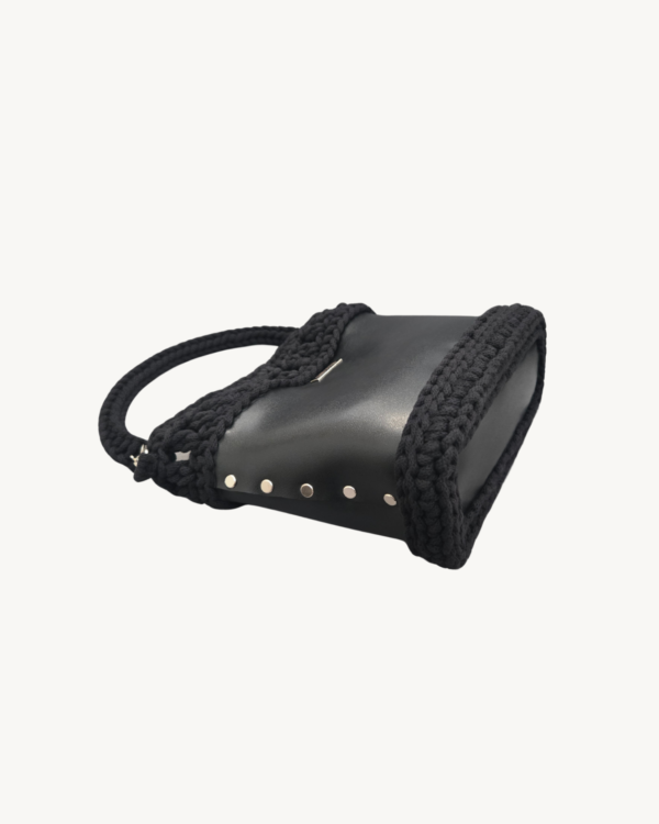 Side-lying view of Vintage Punk Vegan Leather Laced Rhythm Handbag in black showing the structured bottom, Chicago screws, and crochet texture